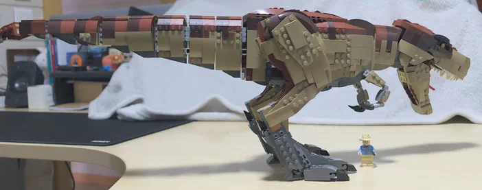 Modèle de dinosaure T-Rex en briques LEGO avec un personnage minifigure à ses côtés.