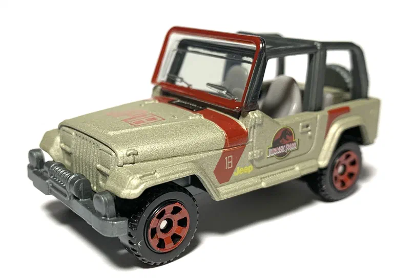 Voiture de jouet Matchbox représentant un Jeep Wrangler #18 beige avec des détails rouges et le logo du parc Jurassique