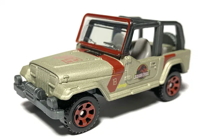 Voiture de jouet Matchbox représentant un Jeep Wrangler #18 beige avec des détails rouges et le logo du parc Jurassique