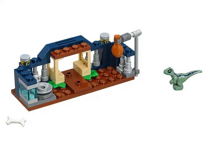 Aire de jeu LEGO Jurassic World avec un bébé Velociraptor vert et des briques bleues.