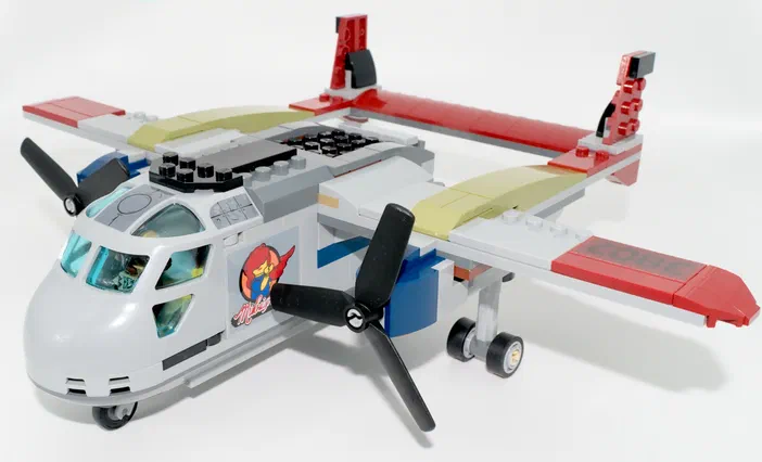 Un avion de transport LEGO gris et rouge avec des hélices noires sur fond blanc.