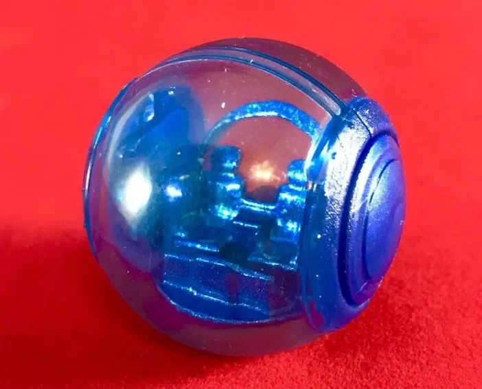 Sphère transparente bleue contenant un mécanisme interne visible, photographiée sur fond rouge.