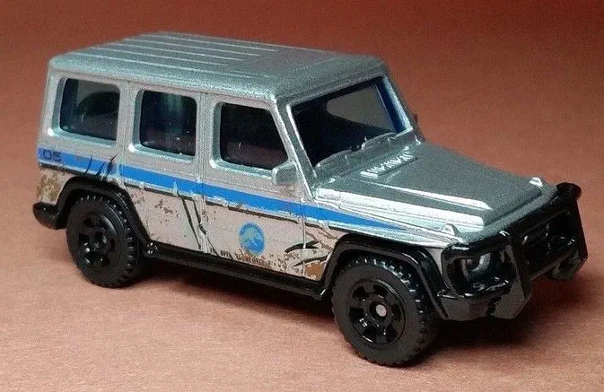 Voiture jouet argentée avec une partie inférieure blanche, ornée de rayures bleues horizontales et d'un numéro 05, affichant un état endommagé simulé par des égratignures noires et de la boue marron.