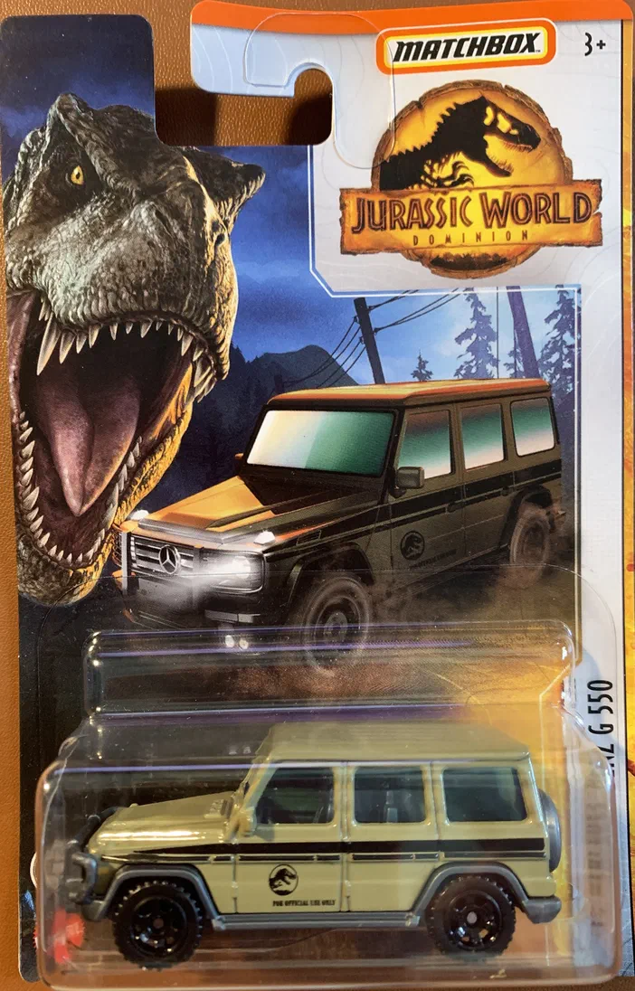 Voiture de collection Matchbox '14 Mercedes-Benz G 550 - Jurassic World Dominion (HBG98) beige avec un T-Rex en arrière-plan.