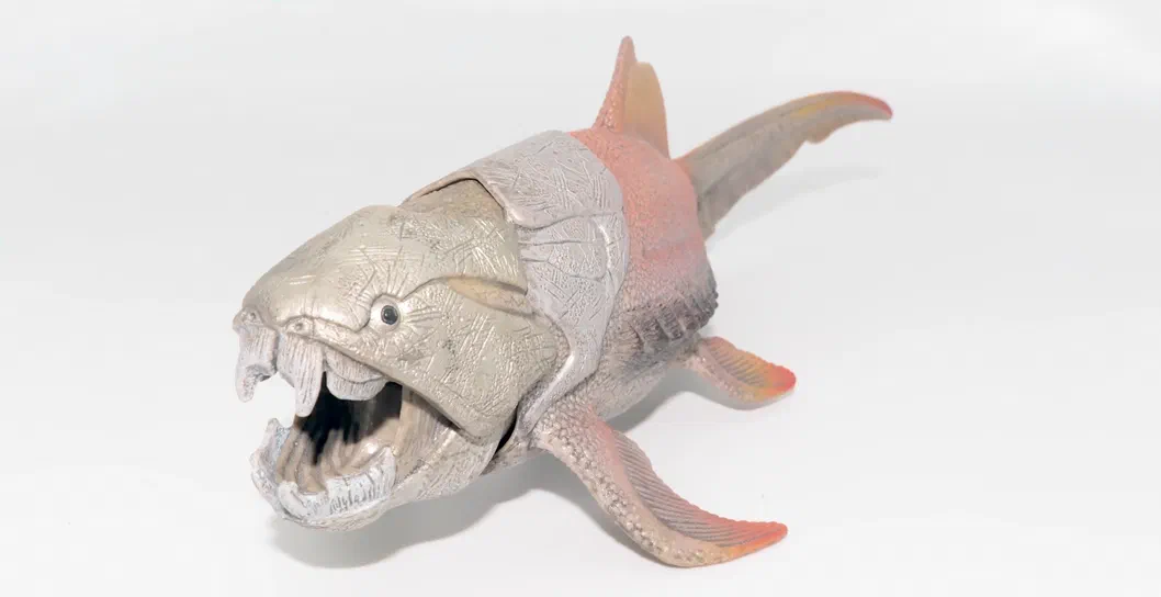 Modèle de dinosaure en plastique aux détails texturés et aux couleurs gris et rouge.