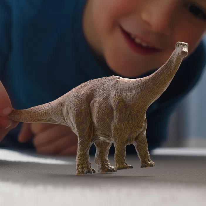 Un jouet dinosaure Brontosaurus en plastique est tenu par la queue d'une main, avec un enfant souriant flou visible dans l'arrièreplan.
