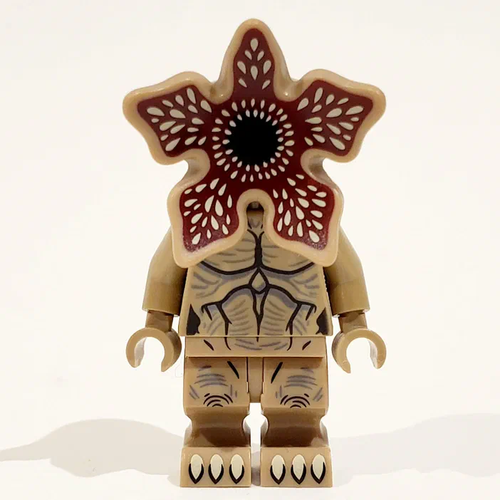 Minifigurine LEGO du monstre Demogorgon de la série Stranger Things avec une tête en forme de fleur rouge et beige et un corps anatomique stylisé sur fond blanc.