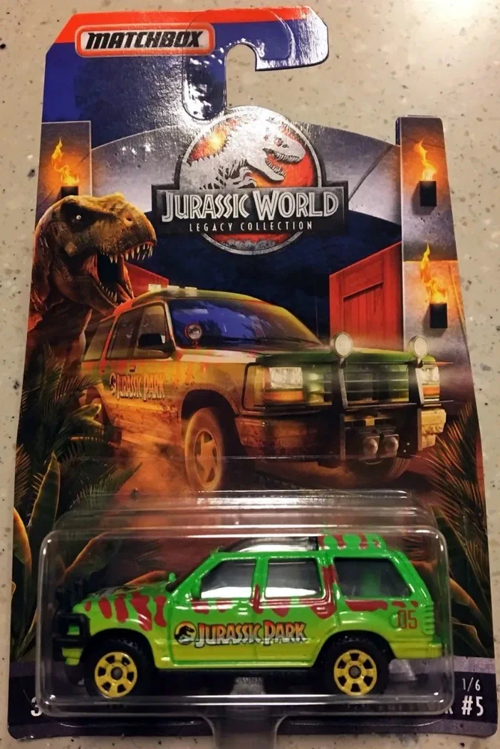 Emballage Matchbox d'une voiture verte 'Jurassic Park' dans la série Legacy Collection de Jurassic World, avec un dinosaure T-Rex en arrière-plan.