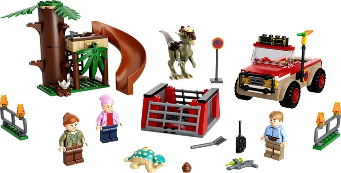 Ensemble de pièces LEGO Jurassic World incluant un dinosaure Stygimoloch, une voiture rouge et beige avec des lumières clignotantes, une structure d'arbre avec toboggan, trois personnages minifigures, divers accessoires comme une pelle, une radio, une arme à eau verte, deux barrières de sécurité orange, et un petit dinosaure bleu vert.