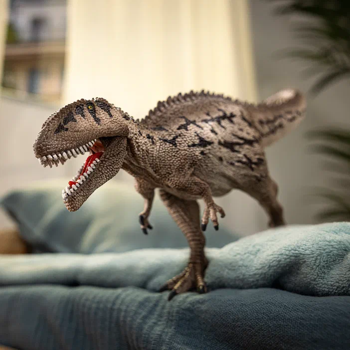 Figurine de dinosaure Carcharodontosaurus Schleich sur un canapé bleu