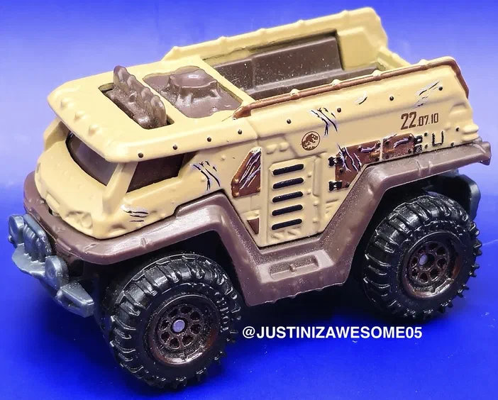 Camionnette Matchbox Jurassic World Dominion de couleur marron avec des détails de combat sur les côtés.