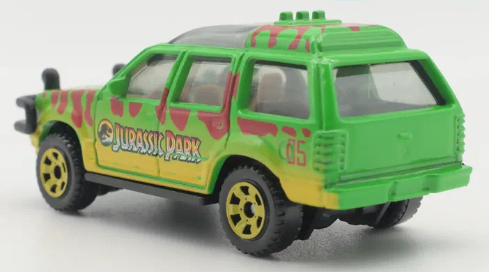 Voiture Matchbox Jurassic Park verte avec des taches rouges et le logo sur la portière.