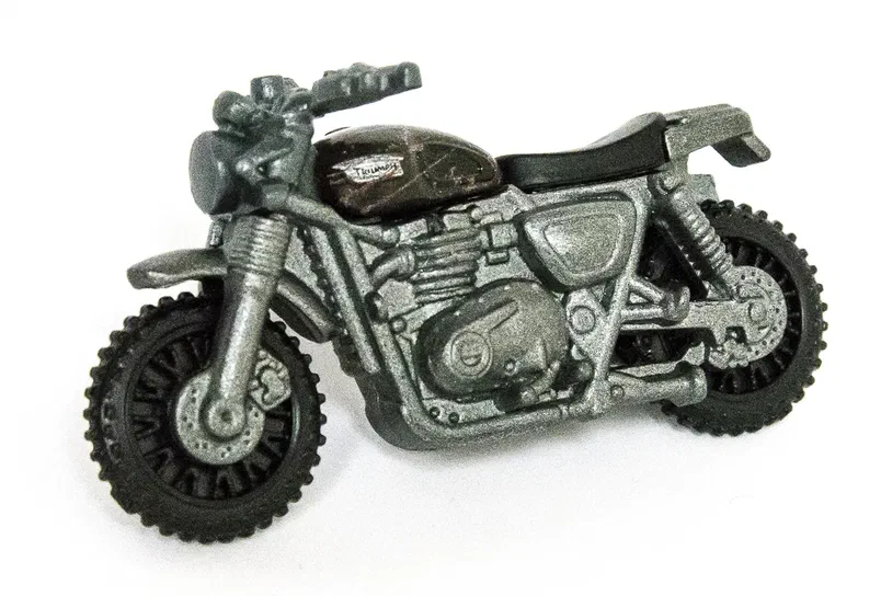 Jouet Matchbox d'une moto Triumph Scrambler de couleur olive vert avec des détails argentés et un réservoir noir.