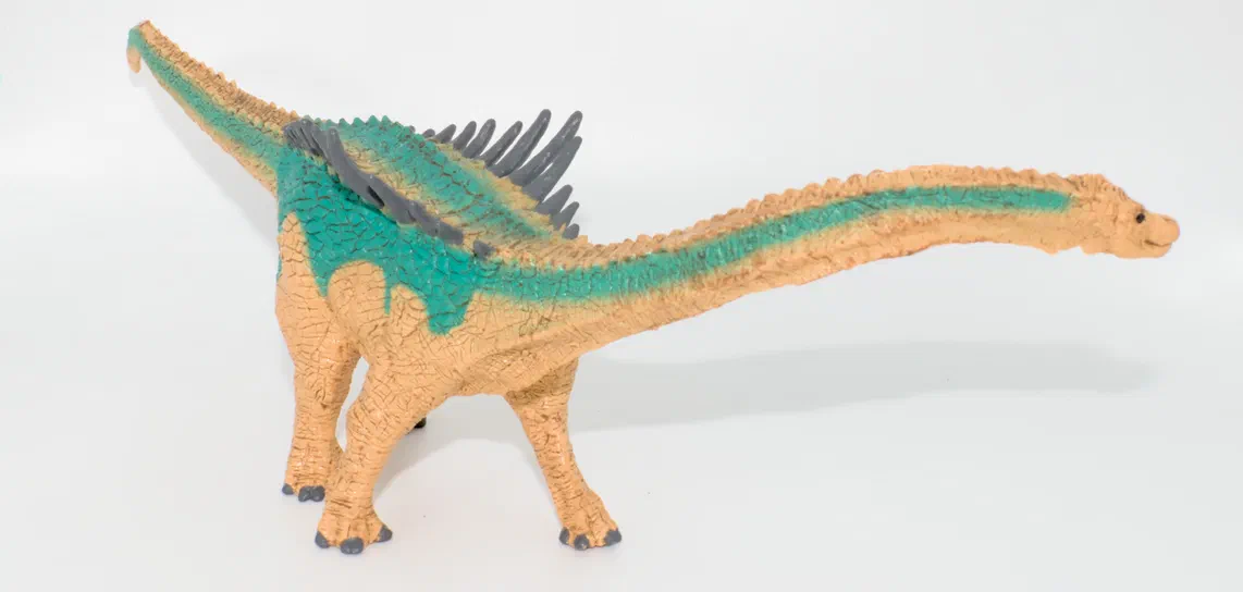 Jouet de dinosaure à long cou avec des écailles vertes et grises sur fond blanc.