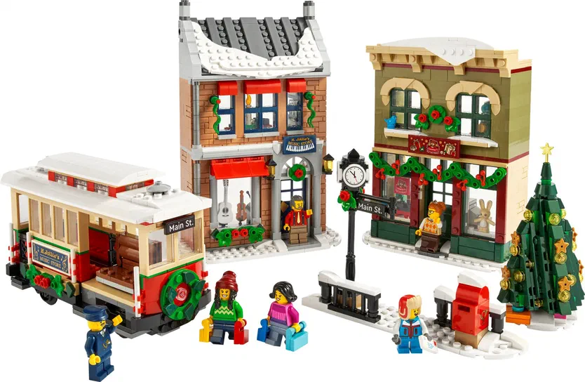 Ensemble de constructions LEGO représentant une scène festive avec un tramway, des boutiques décorées et plusieurs personnages minifigures.