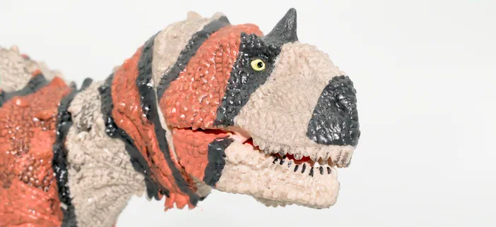 Modèle de dinosaure à tête et cou ornés de rayures noires, rouges et beige.