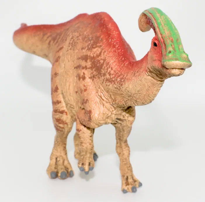 Figurine de dinosaure Schleich Parasaurolophus, avec un bec vert et des marques brunes sur le corps beige.