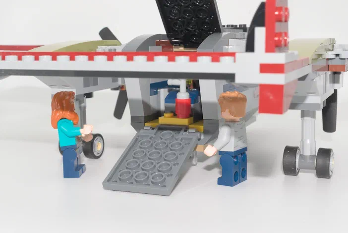 Deux minifigurines Lego se tiennent sous un avion de la série Jurassic World.