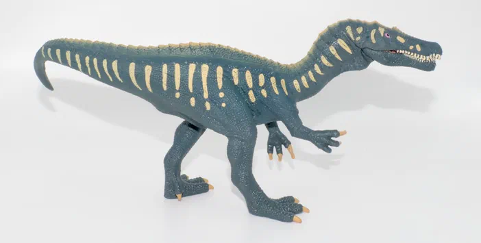 Un jouet de dinosaure bleu avec des marques jaunes sur le dos et les pattes.