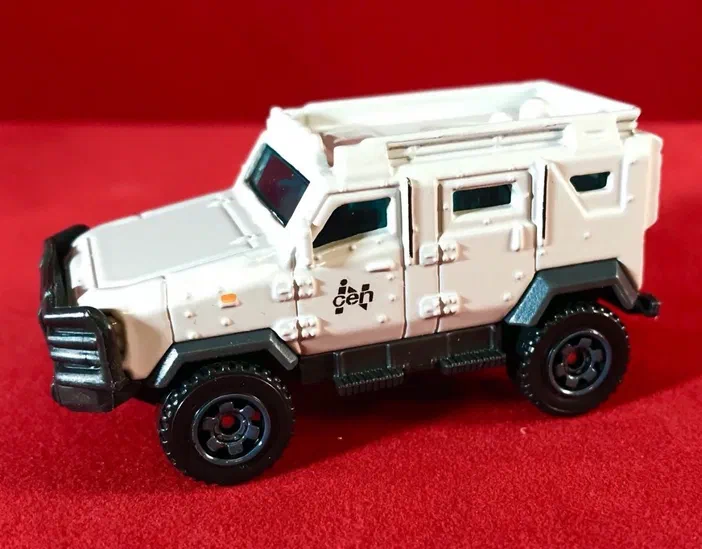 Voiture de jouet Matchbox Textron Tiger blanche avec des détails noirs sur fond rouge.