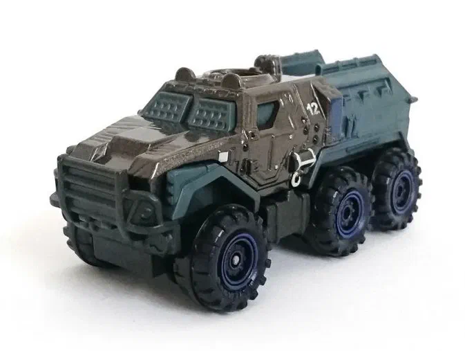 Puce de Matchbox Armored Action Truck gris métallisé avec des roues bleues et un numéro tamponné '12' sur le côté.