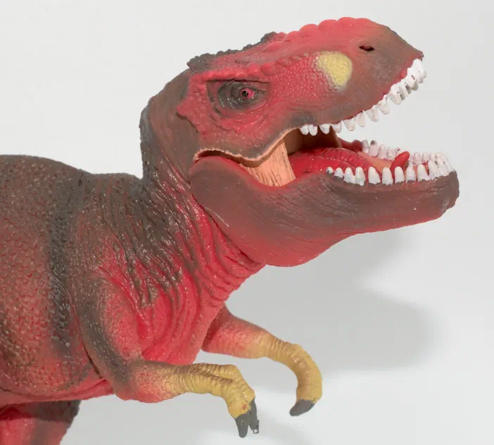 Un jouet de dinosaure rouge avec une gueule ouverte montrant des dents blanches.