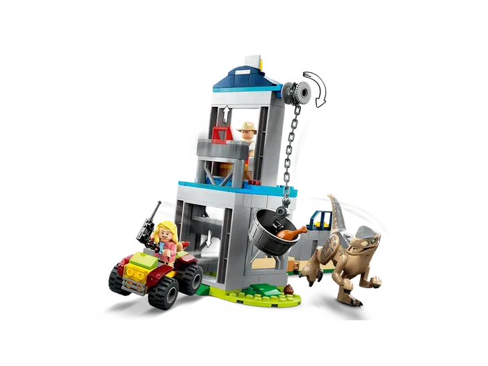 Ensemble de construction LEGO Jurassic World avec une tour grise et bleue, un dinosaure raptor brun tenant une chaîne attachée à un seau noir contenant des pièces orange, et deux personnages minifigurines : l'un sur un quad rouge vert portant une arme noire, l'autre dans la tour.