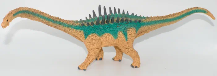 Un jouet de dinosaure à quatre pattes avec un dos vert et des épines noires.