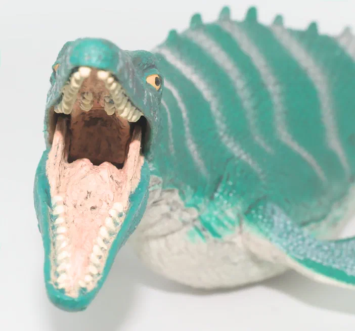 Modèle de dinosaure vert à la gueule ouverte montrant des dents blanches