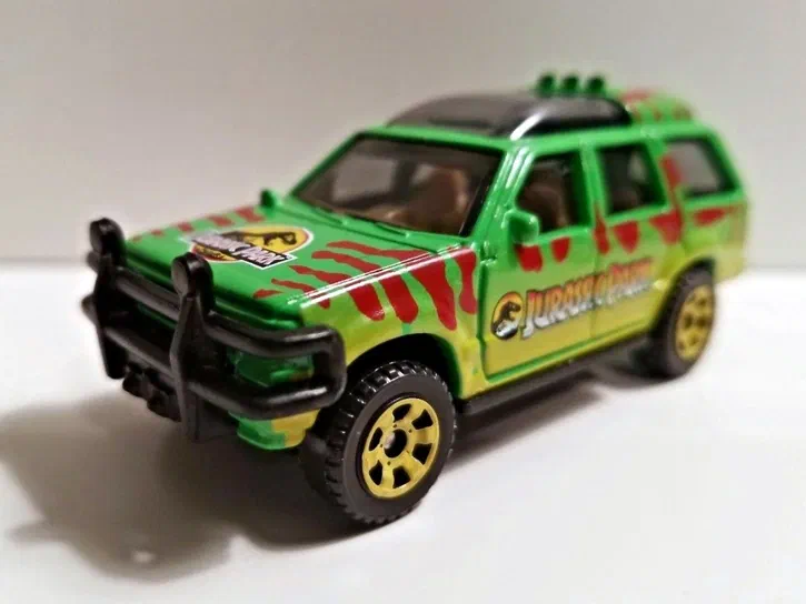 Voiture de collection Matchbox Ford Explorer verte avec des rayures rouges et le logo Jurassic Park.