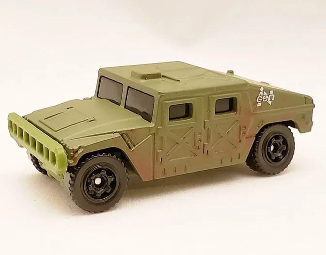 Petite voiture Matchbox verte représentant un Humvee de Jurassic World avec une grille avant et des traces de boue.