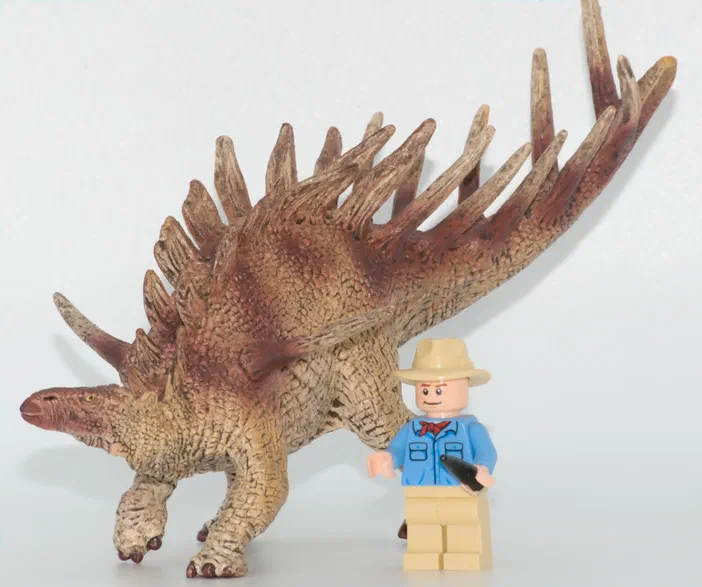 Un jouet de dinosaure Stegosaurus à côté d'un minifigurine LEGO.