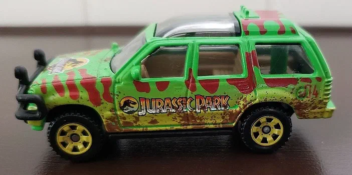 Petite voiture Matchbox Ford Explorer verte avec des rayures rouges et le logo Jurassic Park sur les flancs.