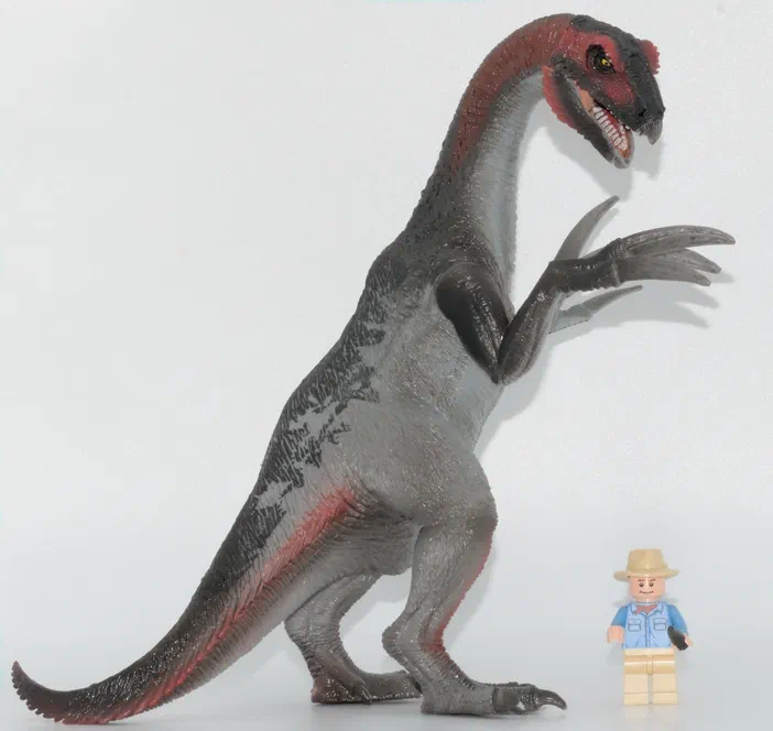 Figurine de dinosaure gris et rouge avec un petit personnage Lego à côté