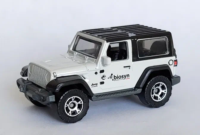 Voiture de collection Matchbox Jeep Wrangler blanche avec toit noir et logos Biosyn Genetics sur les côtés.