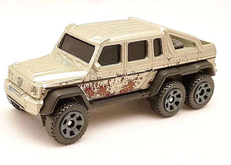 Voiture de collection Matchbox Mercedes-Benz G63 AMG 6x6 en beige avec des traces de boue.