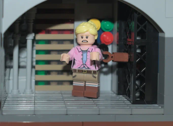 Minifigurine LEGO de Jurassic World dans un décor d'arche avec des colonnes et une grille noire.