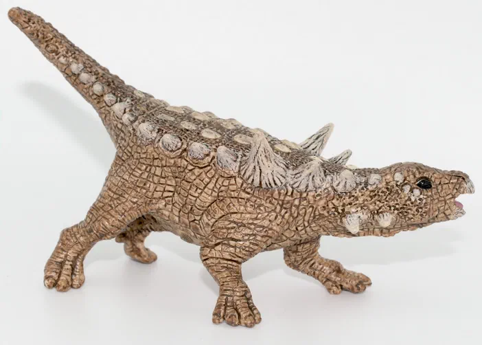 Figurine de dinosaure à dos épineux et écailles détaillées sur fond blanc.