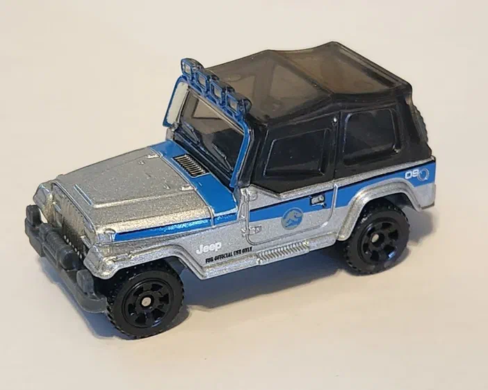 Petite voiture de collection Matchbox Jeep Wrangler argentée et bleue avec un toit noir.
