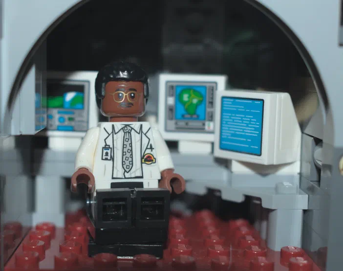 Minion de Lego Jurassic World assis devant des écrans dans une cabine médicale