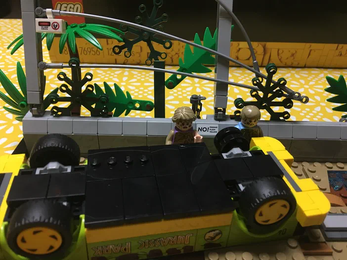 Véhicule LEGO Jurassic World renversé avec deux figurines et des tenons pour ancrer une patte de dinosaure