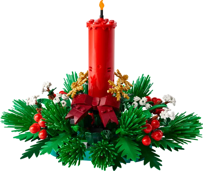 Décoration de table pour Noël en LEGO avec une bougie rouge, des feuilles vertes et des baies rouges.