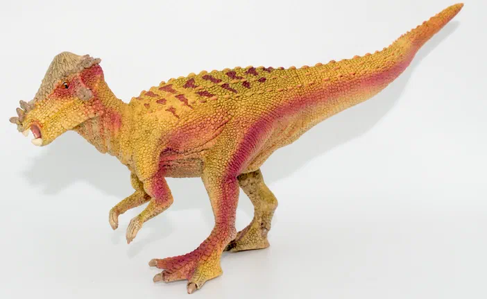 Modèle de dinosaure à deux pattes aux couleurs jaune et rose sur fond blanc
