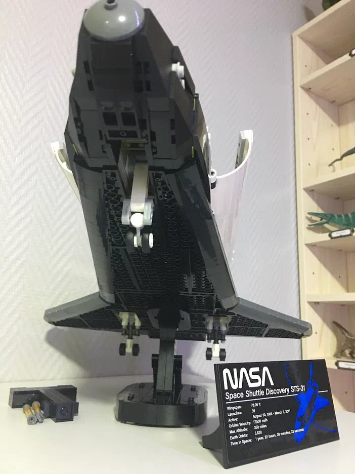 Un modèle de fusée spatiale en LEGO noir sur un socle, avec une étiquette NASA Space Shuttle Discovery STS-31 à côté.