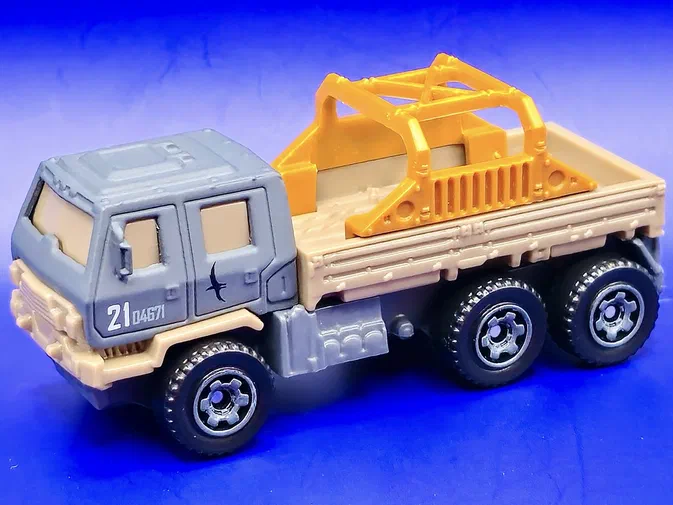 Un camion de secours Matchbox gris et beige avec une structure jaune sur le plateau.