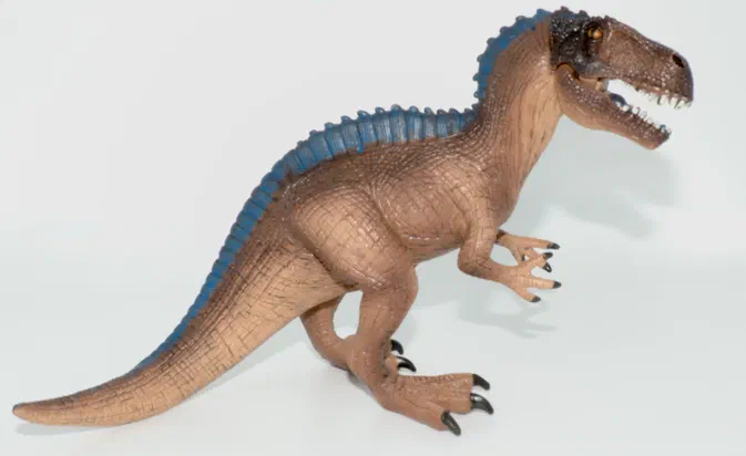 Figurine de dinosaure T-Rex en plastique avec une crête bleue sur le dos