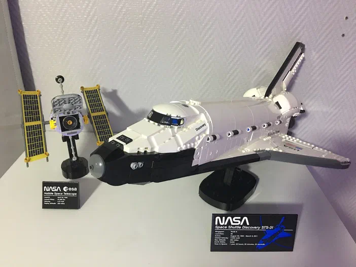 Un modèle de navette spatiale LEGO Discovery avec un télescope Hubble à côté.