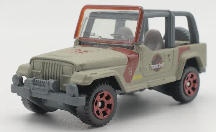 Un jouet Matchbox Jeep Wrangler de Jurassic World avec des détails rouges et gris sur fond blanc.