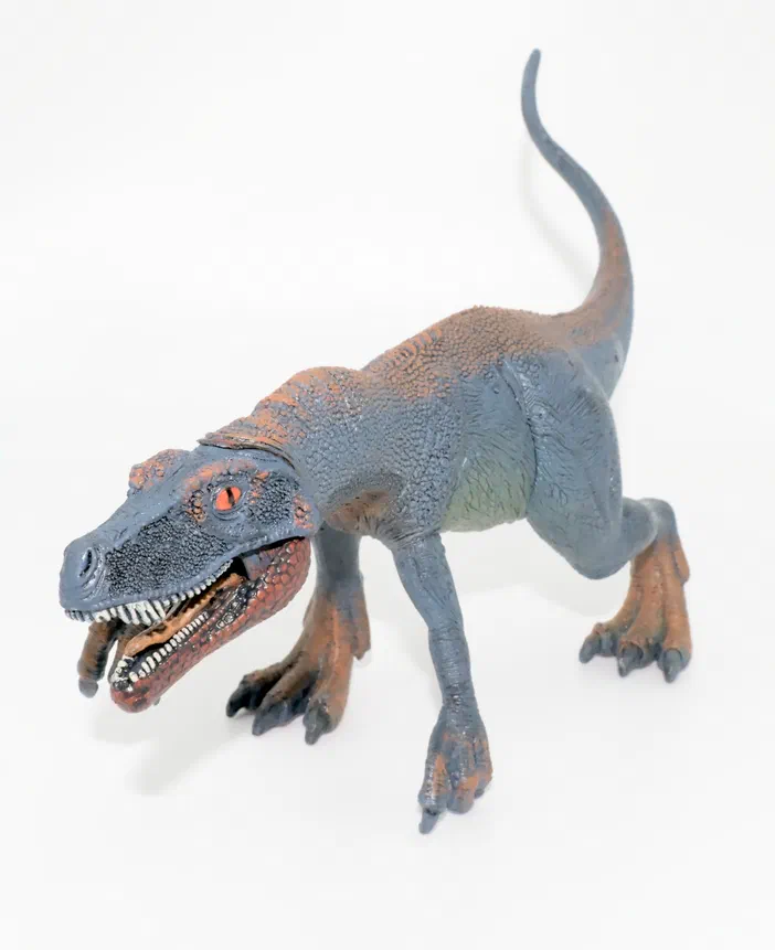 Figurine de dinosaure gris et marron sur fond blanc