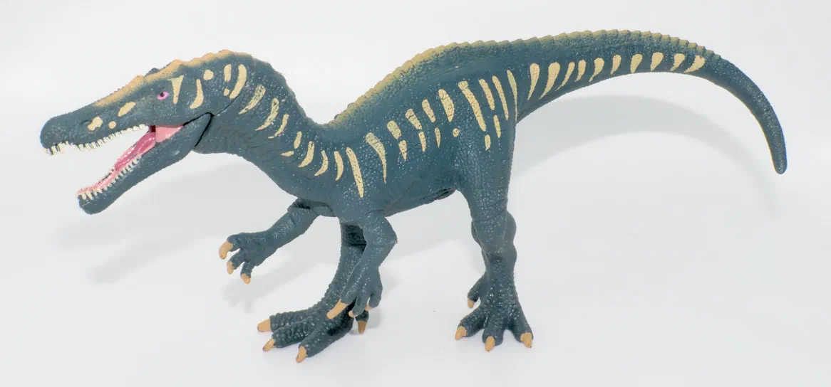 Un jouet de dinosaure bleu avec des marques jaunes sur un fond blanc.
